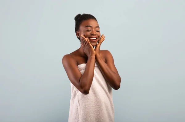 Conceito natural. Atraente senhora afro-americana tocando sua pele suave e impecável nas bochechas, fundo cinza — Fotografia de Stock