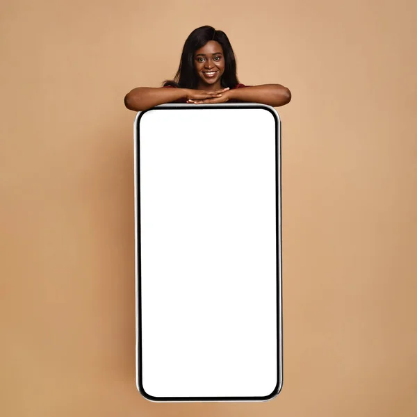 Dame afro-américaine penchée sur un énorme téléphone portable avec écran vide — Photo