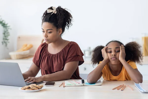 Zwarte vrouw freelancer werken vanuit huis, verveelde dochter zitten door — Stockfoto