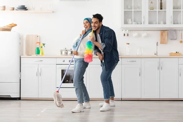 Alegre muçulmano casal limpeza chão e se divertindo na cozinha — Fotografia de Stock