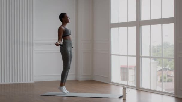 Desportivo afro-americano mulher exercitando com pular corda em casa — Vídeo de Stock