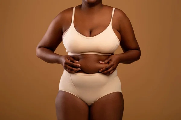 Curvy mujer afroamericana en ropa interior sosteniendo pliegues de grasa —  Fotos de Stock