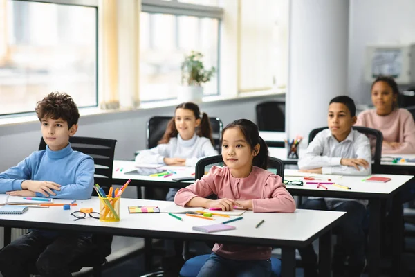 Portret van gefocuste diverse leerlingen aan het bureau in de klas — Stockfoto