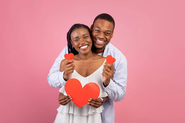 Szczęśliwy czarny mężczyzna i kobieta trzyma papierowe serca — Zdjęcie stockowe