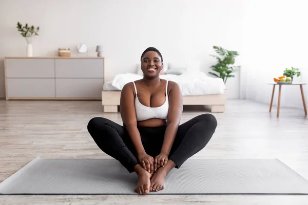Alegre más tamaño negro mujer haciendo yoga en la alfombra deportiva en casa, espacio libre —  Fotos de Stock