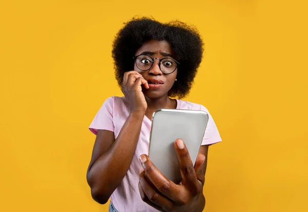 휴대 전화를 들고 있는 아프리카계 미국 여성 이 노란 배경에 대한 나쁜 소식, 사진 또는 메시지를 보고 두려워하고 있습니다. — 스톡 사진
