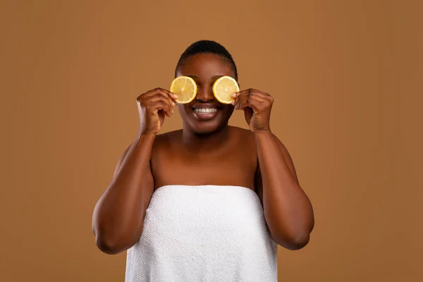 Чорна жінка прикриває очі половинками апельсина — стокове фото