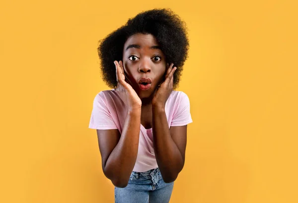 Inacreditável. Chocado Africano americano senhora com boca aberta e mãos em bochechas posando sobre fundo amarelo — Fotografia de Stock