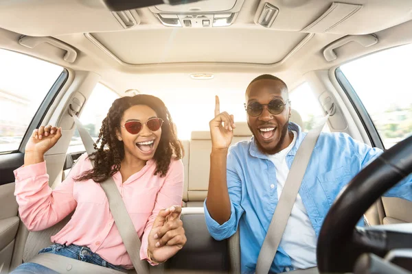 Eccitato coppia nera in occhiali da sole godendo di musica guida auto di lusso — Foto Stock