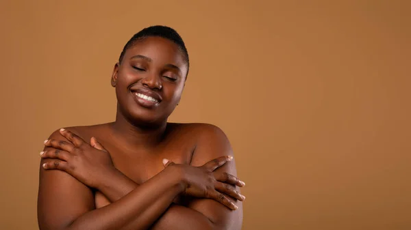 Портрет красивой черной женщины плюс размер обнимающей себя — стоковое фото