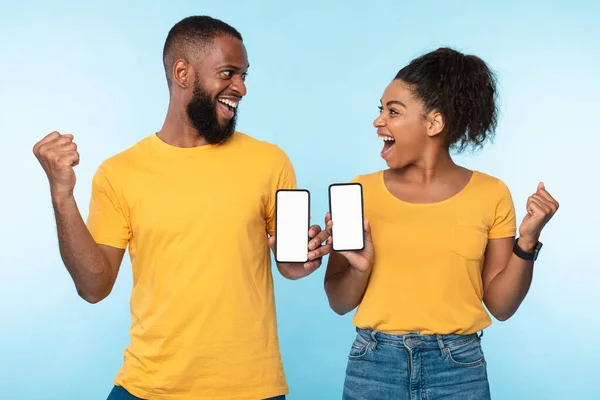 Spännande över denna nya mobilapp. Överlycklig svart par håller smartphones med mockup för design, gör JA gester — Stockfoto
