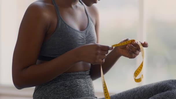 Concepto de adelgazamiento y pérdida de peso. Mujer negra irreconocible sosteniendo cinta métrica en las manos — Vídeo de stock