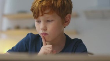 Düşünme süreci. Düşünceli kızıl saçlı çocuğun yakın plan portresi. Yeni bir resim düşünüyor, evde oturuyor.