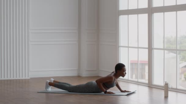 Mujer negra deportiva practicando yoga, haciendo la postura de langosta del avión para el entrenamiento de la espalda — Vídeos de Stock