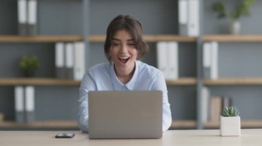 Şirket ödülü. Genç bayan ofis çalışanı işyerinde oturuyor, e-posta alıyor ve okuyor.