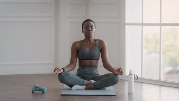 Młoda Afroamerykanka medytująca w pozycji lotosu w domu — Wideo stockowe