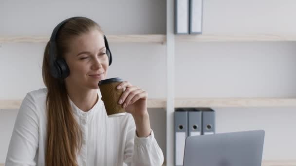 Un descanso en el trabajo. Emprendedora escuchando música y tomando café en la oficina — Vídeos de Stock