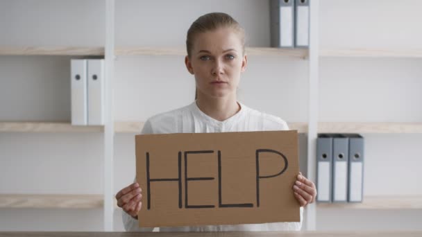 Νεαρή γυναίκα υπάλληλος που κρατά αφίσα με επιγραφή βοήθειας στο χώρο εργασίας στο γραφείο — Αρχείο Βίντεο