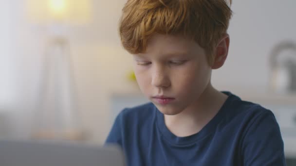 Närbild porträtt av söt liten rödhårig pojke skriva på laptop hemma, studera främmande språk distans, slow motion — Stockvideo