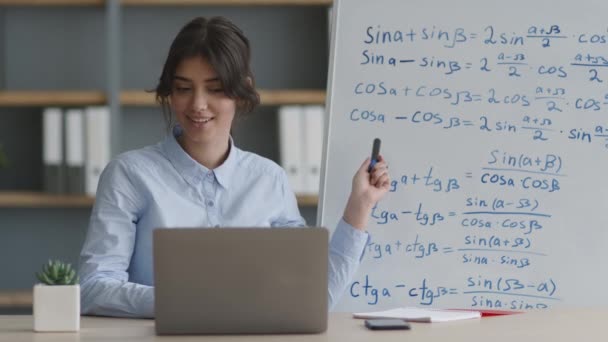 オンライン指導の概念。若い女性がeラーニングを実践し、ホワイトボード上の数式を学生に説明する — ストック動画