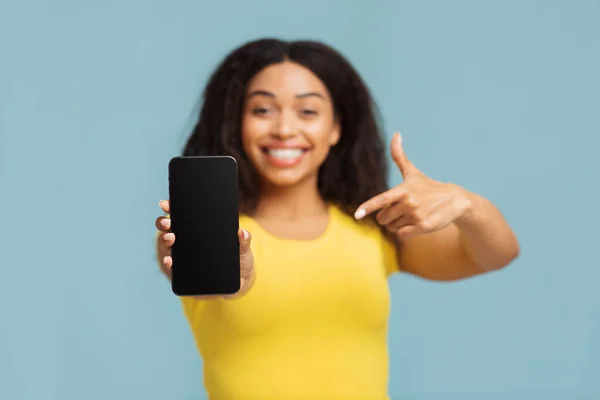 Gambar mockup wanita kulit hitam yang menunjuk smartphone dengan layar kosong, menunjukkan tempat untuk desain atau iklan — Stok Foto