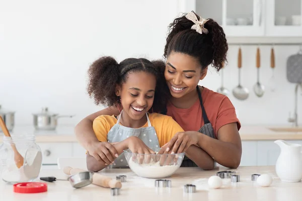 Schwarze Mutter zeigt ihrer Teenie-Tochter, wie man Plätzchen backt — Stockfoto