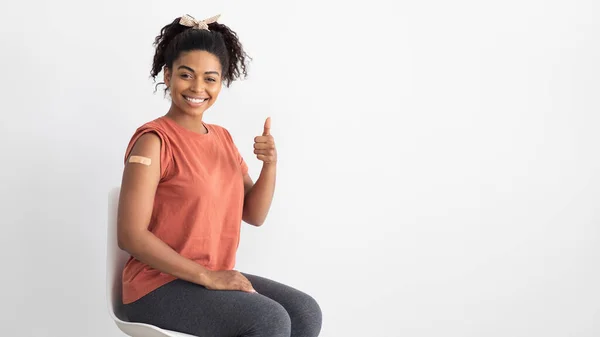 Χαρούμενη Αφρο-Αμερικανίδα ασθενής που έδειξε τον αντίχειρα της και εμβολιάστηκε. — Φωτογραφία Αρχείου