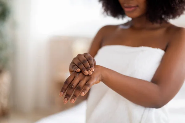 Irreconocible joven afro dama aplicando crema de manos después de la ducha, usando toalla blanca en el interior, espacio de copia — Foto de Stock
