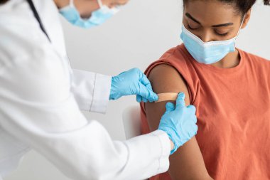 Hemşire kadın hasta koluna sıva yapıyor.