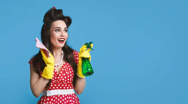 Senhora pinup emocional em roupas de estilo retro posando com pano e spray detergente no fundo do estúdio azul, banner — Fotografia de Stock