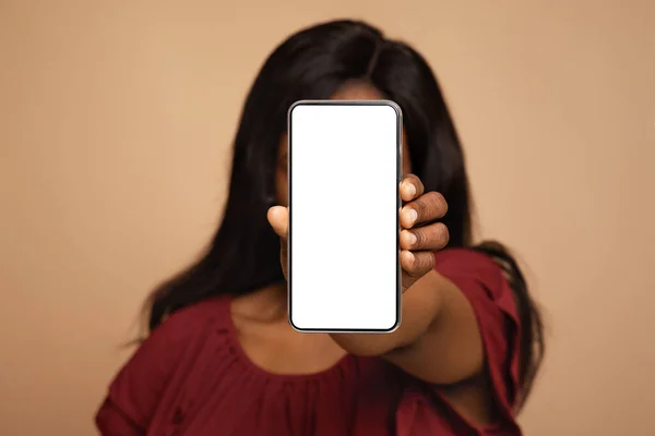 Черная женщина закрывает лицо пустым экраном сотового телефона, макет — стоковое фото