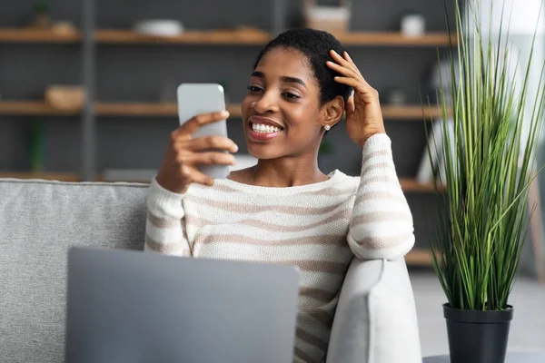 Giovane donna afroamericana che utilizza smartphone e laptop a casa — Foto Stock