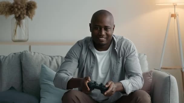 Homem negro jogando e perdendo Videogame sentado no sofá interior — Vídeo de Stock