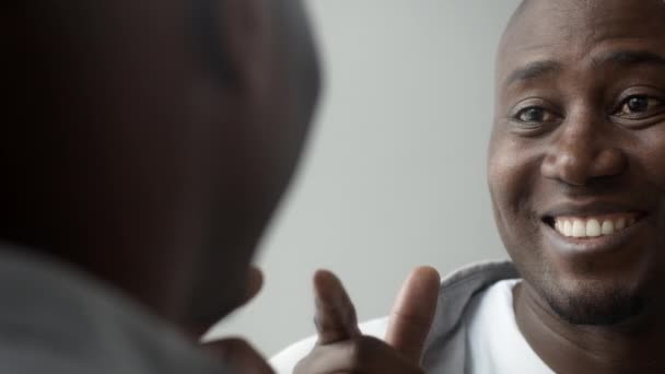 Självsäker medelålders afrikansk man som blinkar till reflektion i spegeln inomhus — Stockvideo