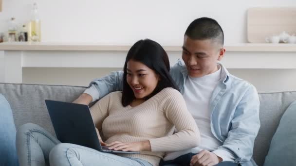 Ασιατικό ζευγάρι παίζει παιχνίδι στο φορητό υπολογιστή διασκεδάζοντας στο σπίτι — Αρχείο Βίντεο