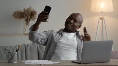Siyah adam iş yerindeki telefon pozunda selfie çekiyor.
