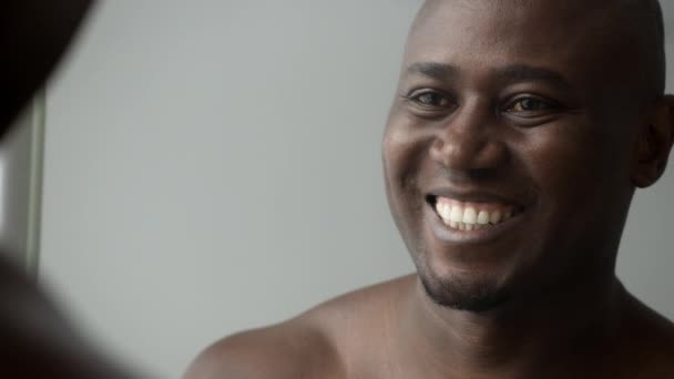 Noir homme souriant à son reflet dans le miroir dans la salle de bain — Video