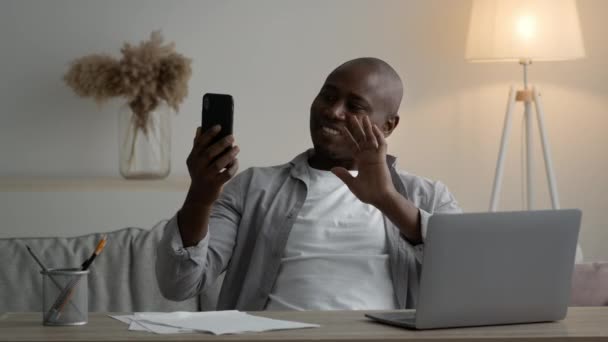 Glad afroamerikansk man videosamtal Använda telefon på arbetsplatsen — Stockvideo