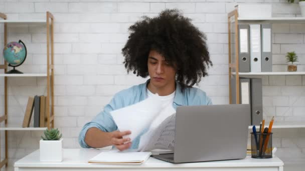Olycklig student Guy tittar igenom Papers sitter på laptop Inomhus — Stockvideo