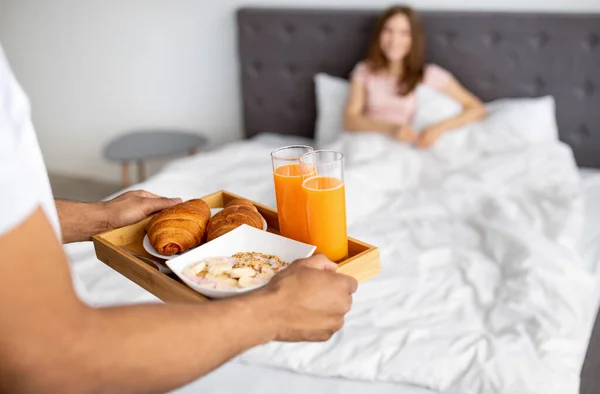 Romantyczny czarny facet przynosi śniadanie do łóżka dla swojej ukochanej kobiety, zbliżenie rąk — Zdjęcie stockowe
