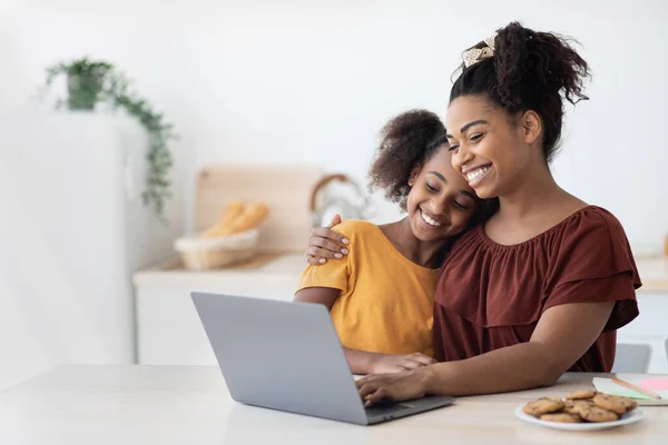 Cute black mother and kid using laptop together