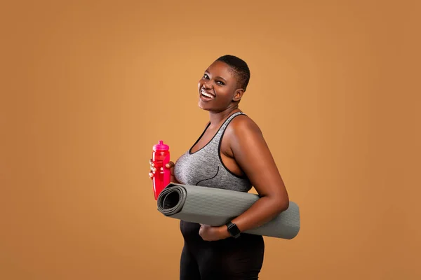 Μαύρη γυναίκα ποζάρει με το στρώμα και το νερό μπουκάλι στο στούντιο — Φωτογραφία Αρχείου