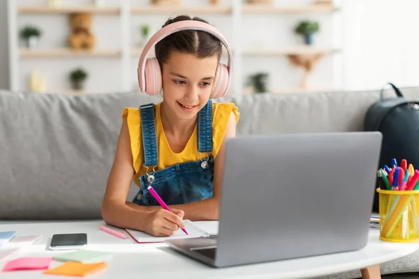 女孩坐在办公桌前，用笔记本电脑，在抄本里画画 — 图库照片