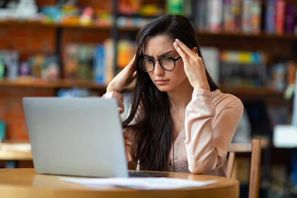 Problemas no trabalho. Mulher latina exausta freelancer cansado após o trabalho no laptop, tendo dor de cabeça, sentado à mesa no café — Fotografia de Stock
