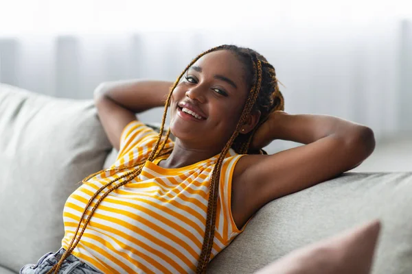 Primer plano de la mujer negra feliz reclinado en el sofá en casa —  Fotos de Stock