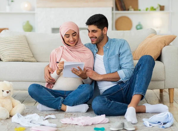 Preparação para o parto. Casal muçulmano grávida fazendo checklist de coisas do bebê antes de ir para a maternidade — Fotografia de Stock
