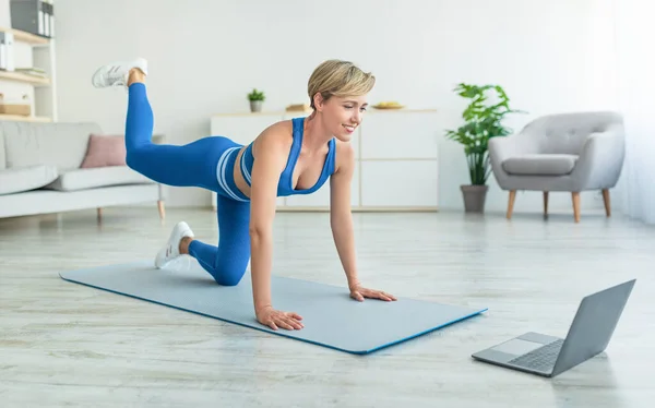 Glimlachende vrouw in sportkleding doen ezel trappen oefening — Stockfoto