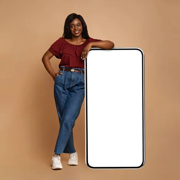 Jolie femme noire debout par un énorme smartphone avec écran vide — Photo