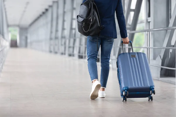 Vista trasera del hombre irreconocible caminando con la maleta en la terminal del aeropuerto — Foto de Stock