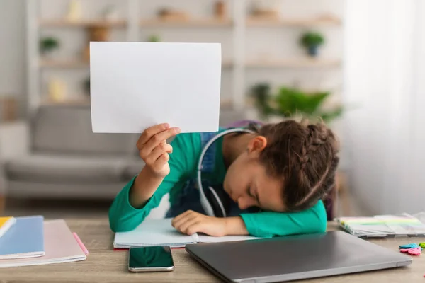 Cansada chica de la escuela durmiendo en mesa sosteniendo papel —  Fotos de Stock
